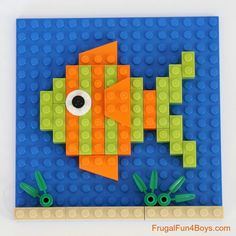 an orange and green fish made out of legos on top of a blue surface