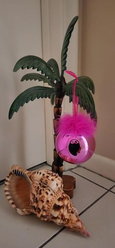 a pink flamingo ornament next to a seashell and a palm tree