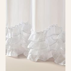 three white ruffled curtains hanging on the side of a window