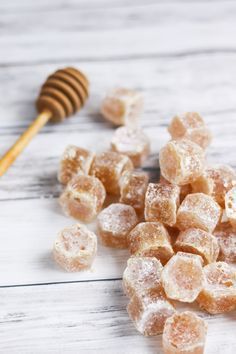 sugared honeycombs and a wooden spoon on a white wood table with a honey comb