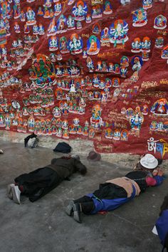 several people laying on the ground in front of a wall