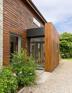 an exterior view of a modern home with wood siding and glass doors on the outside