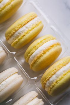 several yellow and white macaroons are in a plastic container