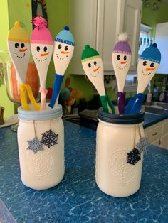 four snowman spoons in mason jars on a kitchen counter with blue counters and white cabinets