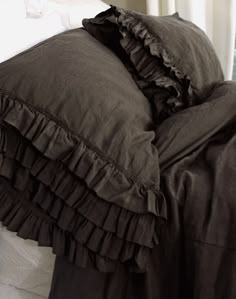 a bed with ruffled black sheets and pillows