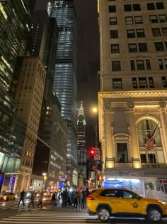 a yellow taxi cab driving down a street next to tall buildings in new york city