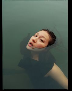 a woman floating in the water with her hair blowing back and looking up at something