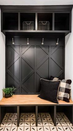 a wooden bench sitting in front of a black book shelf with baskets on top of it