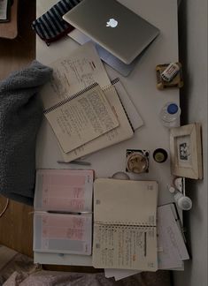 an open laptop computer sitting on top of a desk next to papers and other items