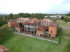 an aerial view of a large brick building in the middle of a green field with lots of trees