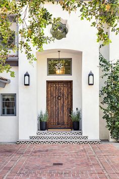 a white house with a wooden door and two planters