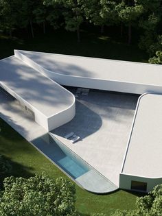 an aerial view of a modern house in the middle of trees and grass, with a swimming pool