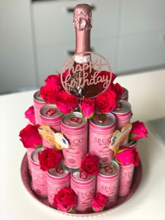 a birthday cake made out of pink cans and red roses with a bottle on top