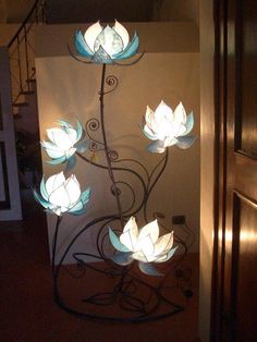 a metal sculpture with white flowers on it in front of a door and stairs leading up to the second floor