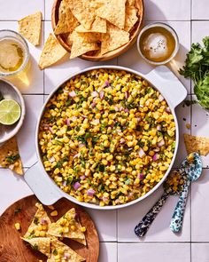 corn salsa with tortilla chips and lime wedges on the side next to it