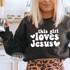 a woman with blonde hair wearing a black sweatshirt that says this girl loves jesus on it