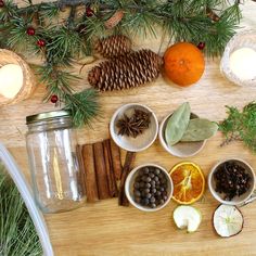 an assortment of fruits and spices on a wooden table with pine cones, oranges, cinnamon sticks, apples, peppercorn