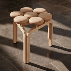 a stool made out of wood with six wooden circles on the top and bottom, sitting on a tile floor