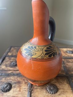 an orange vase sitting on top of a wooden table