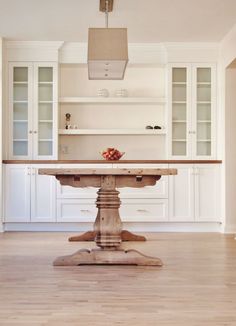 a kitchen with white cabinets and an island table in front of the stove top oven