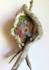 a piece of driftwood with a colorful object in it's center sitting on a white surface