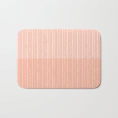 a pink and white bath mat with horizontal stripes on the bottom, in front of a white background