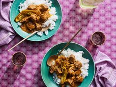 two plates filled with meat and rice on top of a purple table cloth next to wine glasses