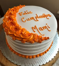 a white cake with orange icing and writing on it that says, faliz cumplanos manu