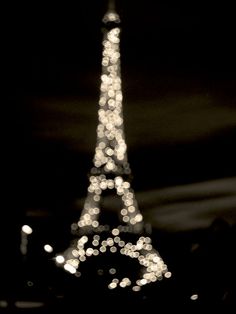 the eiffel tower lit up at night in black and white with lights on it