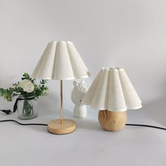 two lamps sitting on top of a table next to a vase with flowers in it