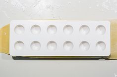 a white box with eight holes in it sitting on top of a yellow piece of paper