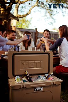 a group of people sitting at a table with coolers and drinks in front of them