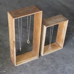 two wooden boxes with necklaces hanging from them on concrete floored area next to each other