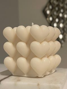 a white heart shaped candle sitting on top of a marble block