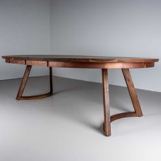 a wooden table sitting on top of a white floor next to a brick wall in an empty room