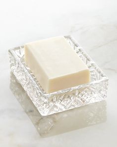 a bar of soap sitting on top of a glass container next to a white marble counter