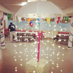 a white umbrella sitting in the middle of a room filled with balloons and confetti