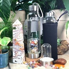 two water bottles are sitting next to each other on a table with rocks and plants in the background