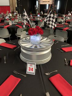 the centerpieces are decorated with red flowers and black tablecloths, along with silverware