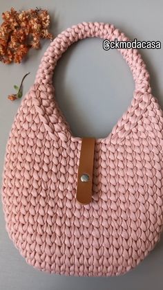 a pink handbag sitting on top of a table next to a small leafy plant