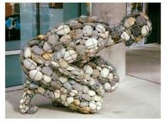 a snake sculpture made out of rocks on the side of a building with caption that reads, her dei lignize ata