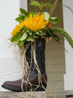 a cowboy boot with sunflowers in it sitting on the front step of a house