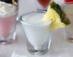 three glasses filled with different types of drinks on top of a white table next to each other