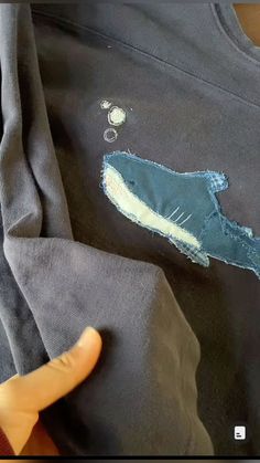 someone is stitching an applique on the back of a sweatshirt that looks like a shark