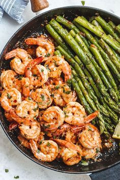 shrimp and asparagus in a skillet with lemon wedges on the side