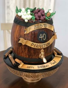 a birthday cake made to look like a barrel with wine and grapes on top that says aged to perfection