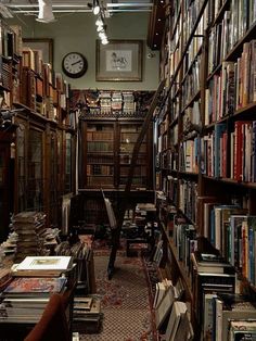 an old library with many books on the shelves and a clock hanging from the ceiling