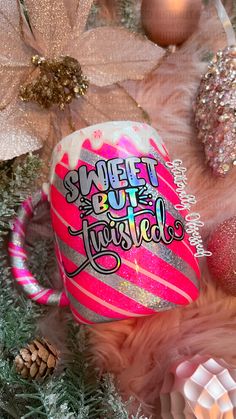 a pink coffee mug with the words sweet but twisted on it surrounded by christmas decorations