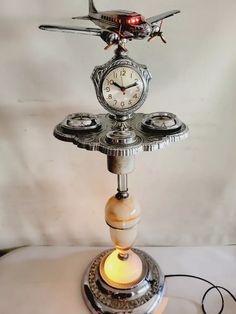 a clock on top of a table with an airplane in the middle and light underneath it