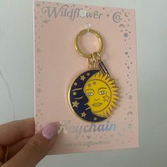 a hand holding a keychain with the sun and moon on it's side